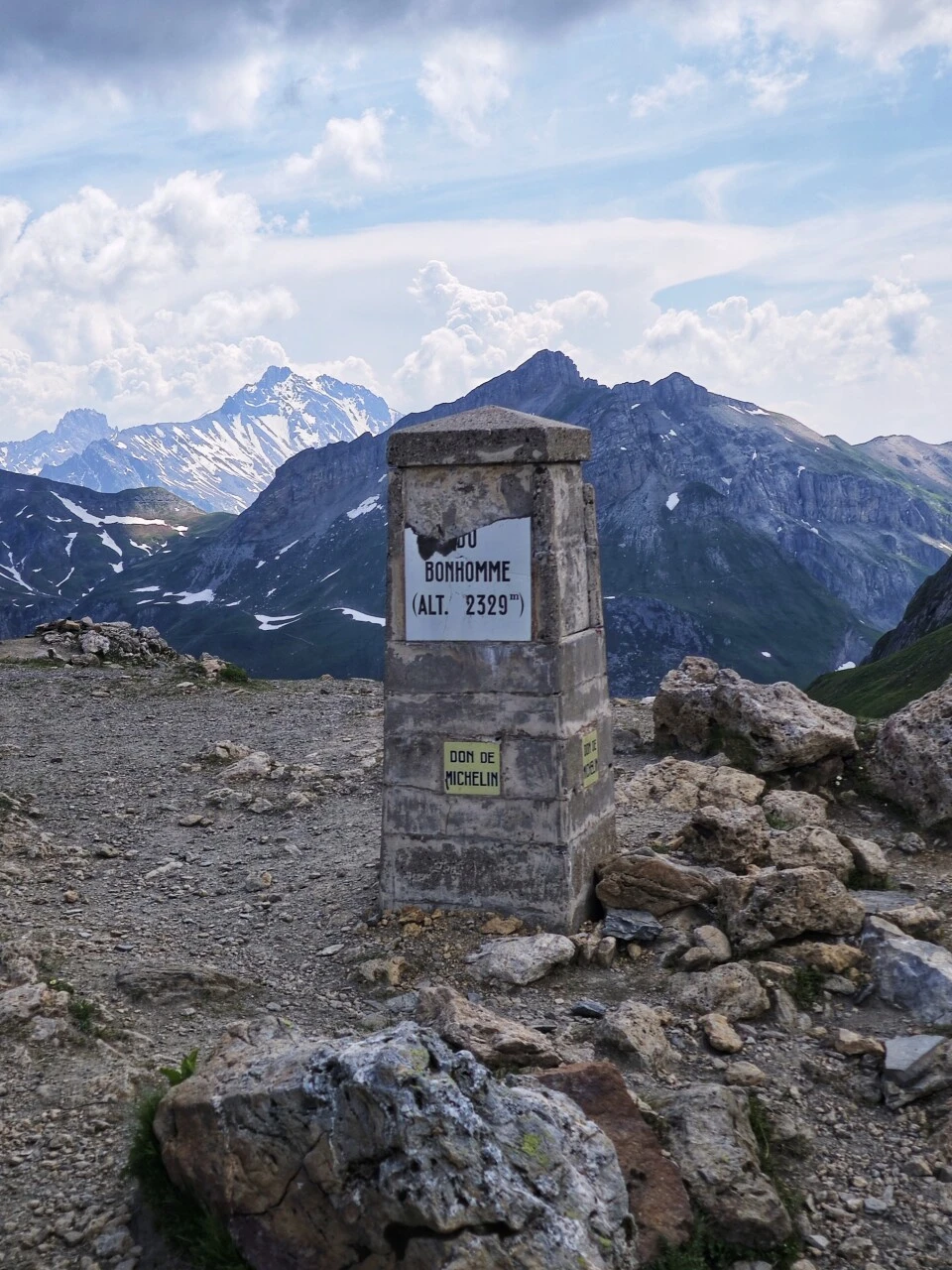 Stone marker at Col du Bonhomme (2,329 m), between mist and snowy peaks